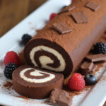 Rocambole de Chocolate finalizado, polvilhado com açúcar de confeiteiro e acompanhado de morangos frescos.