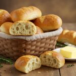 A basket of Crusty Chewy French Bread Rolls, golden and fresh from the oven, served with butter and herbs, perfect for any meal.