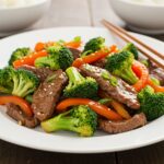 Easy Beef and Broccoli Recipe - Deliciously plated beef and broccoli stir-fry garnished with sesame seeds and served with rice.