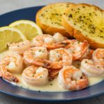 Delicious Easy Creamy Garlic Shrimp on a plate, served with garlic bread and lemon wedges, highlighting a perfect meal for seafood lovers.