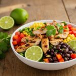Final presentation of Easy Zesty Southwest Chicken Salad Bowl on a wooden table, featuring vibrant colors and garnished with lime wedges and cilantro.