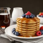 A stunning display of fluffy pancakes stacked high, beautifully topped with maple syrup and fresh berries, perfect for breakfast.