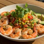 Delicious grilled shrimp bowl with avocado, corn salsa, and creamy garlic sauce, a perfect harmony of flavors on a rustic table.