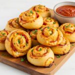 Delicious High Protein Pepperoni Pizza Rolls served on a wooden board with marinara sauce, perfect for a snack.