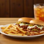 Final presentation of Philly Cheesesteak Sloppy Joes accompanied by crispy fries, perfect for a hearty meal.