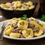 Delicious Philly cheesesteak tortellini pasta served on a rustic dining table, showcasing creamy flavors and hearty ingredients that entice the appetite.