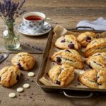 Golden-brown Blackberry Lavender White-Chocolate Scones displayed on a rustic wooden table with tea and fresh lavender.