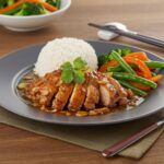 Final presentation of caramelised soy chicken in garlic ginger broth with rice, a delicious and wholesome meal.