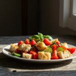 Final presentation of a cold Panzanella salad, featuring vibrant tomatoes, cucumbers, and aromatic herbs, a perfect dish for warm weather dining.