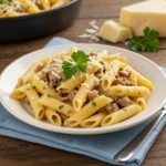 Final presentation of creamy cheesy penne with garlic butter ground beef, showcasing a delicious plate in a cozy dining atmosphere.