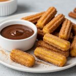 Delicious crispy air fryer churro bites served with chocolate sauce, the perfect treat for sweet lovers.