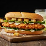 Finished Crispy Chicken Caesar Sandwich on a wooden board, showcasing the crispiness and freshness of ingredients, perfect for a delicious meal.