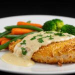 Final presentation of crispy Parmesan chicken with dreamy garlic cream sauce, showcasing a delicious and elegant meal.