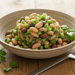 Deliciously presented Dense Bean Salad, ready to be served, featuring a colorful blend of beans and fresh vegetables in a rustic setting.