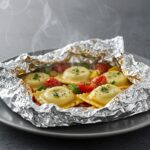 Deliciously cooked foil-pack ravioli dinner served with vibrant vegetables, showcasing an easy and flavorful meal.