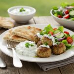 Final presentation of Greek Turkey Meatballs with Tzatziki sauce on a rustic table, highlighting a delicious Mediterranean meal.