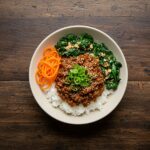 A deliciously crafted Korean Ground Beef Bowl featuring seasoned beef, rice, and vibrant garnishes served on a wooden table.