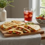 Final display of Mediterranean Quesadillas on a dining table, accompanied by fresh salad and a drink, perfect for a delightful meal.