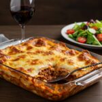 Gorgeous serving of Parmesan Garlic Bacon Cheeseburger Lasagna with layers of cheese and bacon on a dining table.