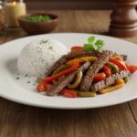 Delicious pepper steak with bell peppers and onions, elegantly plated with a side of rice, an inviting meal.
