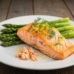 Plated perfectly baked salmon with lemon and dill, accompanied by asparagus, presenting an appetizing and healthy dinner option.