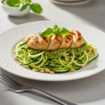 Final presentation of Pesto Zucchini Noodles with Grilled Chicken, showcasing the vibrant dish garnished beautifully for an appetizing look.