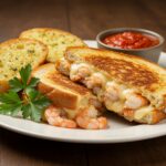 Delicious shrimp-stuffed grilled cheese with garlic bread presented elegantly on a plate; perfect for seafood lovers.