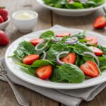 Beautifully arranged Strawberry Spinach Salad ready to serve, showcasing a healthy and delicious meal on a rustic wooden table.