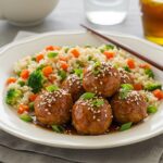 Delicious teriyaki chicken meatballs served on a plate with rice and vegetables, an appetizing presentation for a delightful meal.