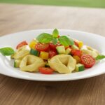 Delicious tortellini with summer veggies, elegantly plated and garnished, showcasing a vibrant and appetizing dish.
