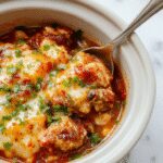 A hearty chicken enchilada casserole in a rustic oval ceramic dish, topped with melted cheese and garnished with fresh cilantro, showcasing layers of shredded chicken, enchilada sauce, and tortillas. The casserole is steaming, with vibrant red sauce and golden cheese visible, set against a warm, inviting fall-themed background with autumn leaves.